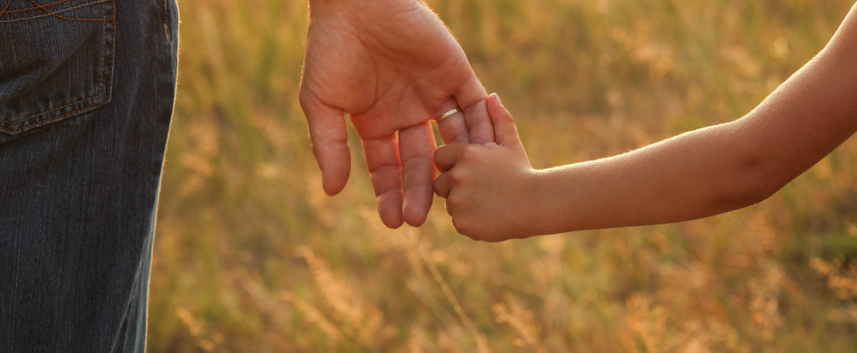 Close-up of a parent holding a child’s hand