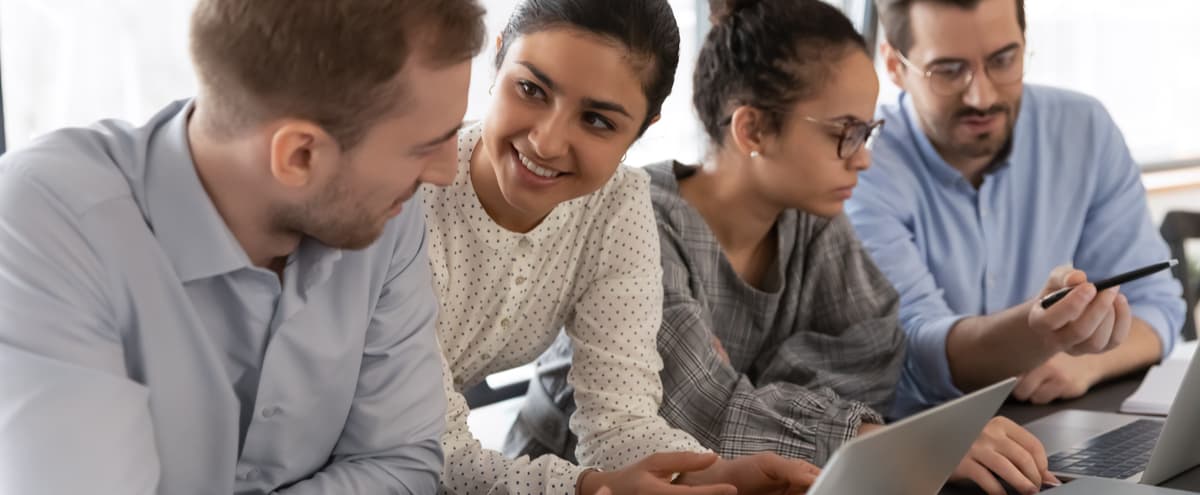 A group of young employees talking and working at a desk.
