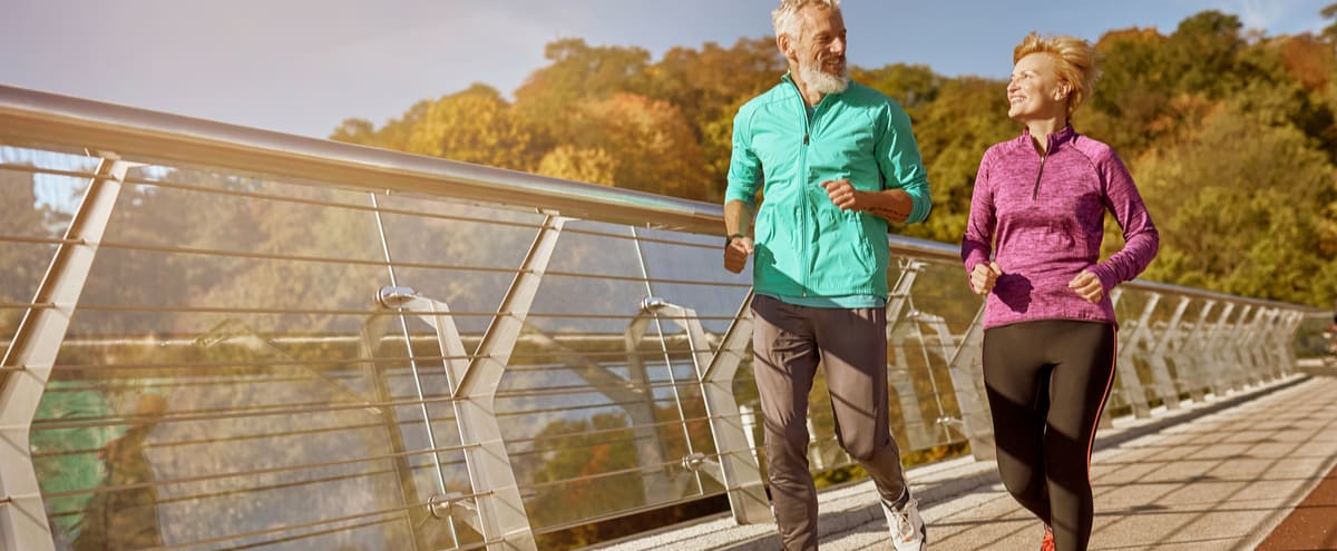 A mature couple jogging across a bridge.