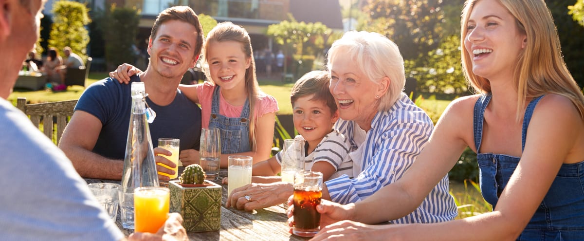 A smiling family sitting around a garden table.