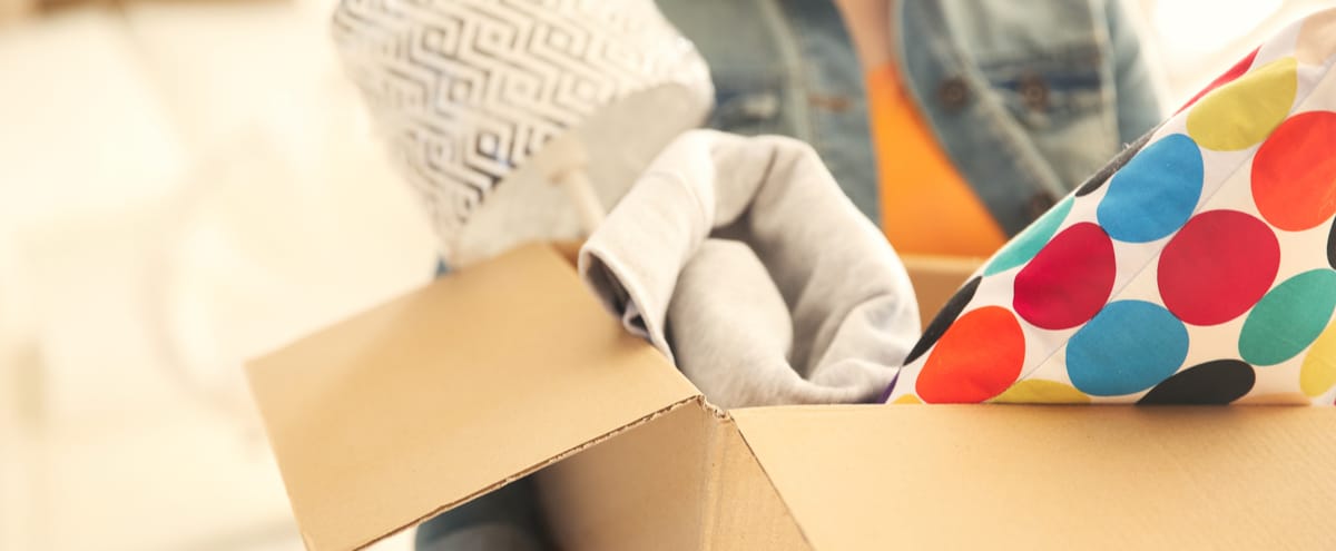 A woman carrying a cardboard box as she moves house.