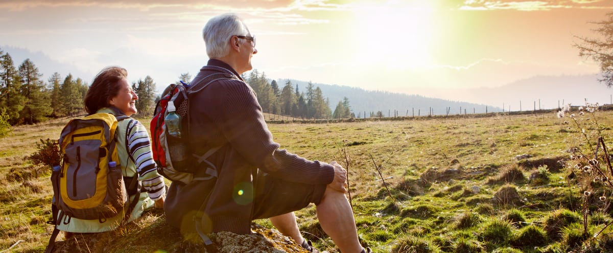 An older couple watching the sunrise on a hike.