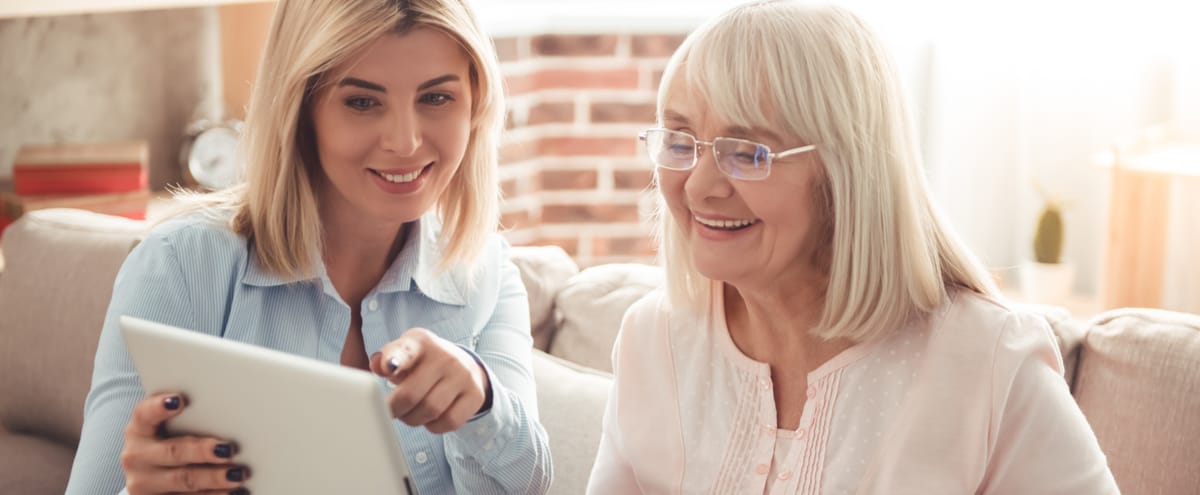 A young adult showing her mum something on a tablet.