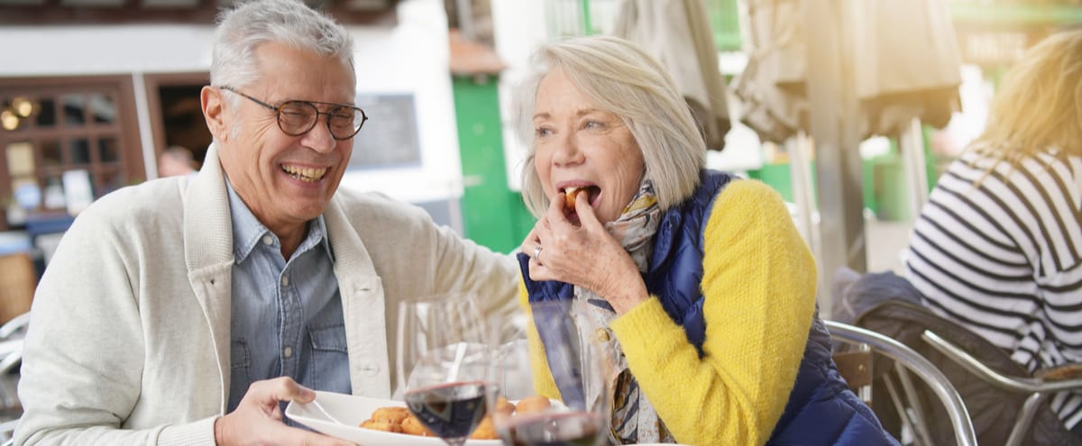 A couple laughing together as they eat al fresco.