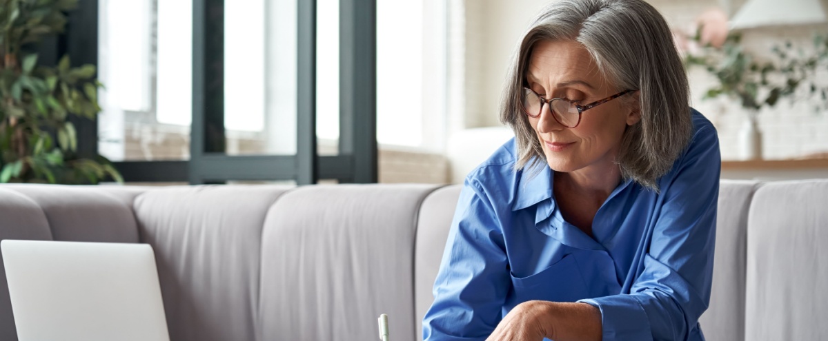 A woman using a laptop and writing notes.