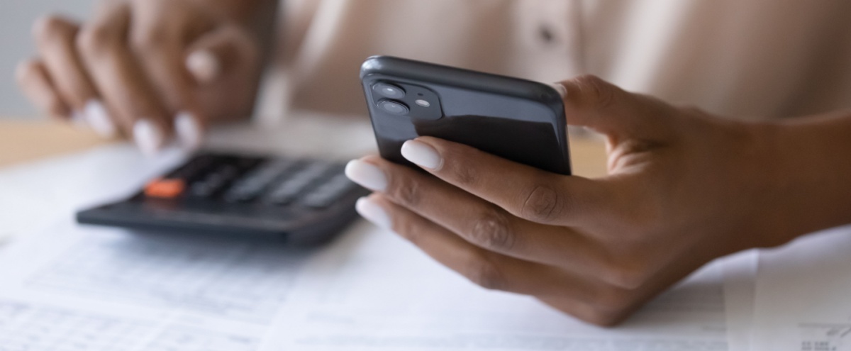 A woman using a calculator while reviewing paperwork.