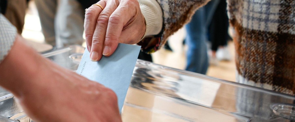 A person putting a ballot paper into a box.