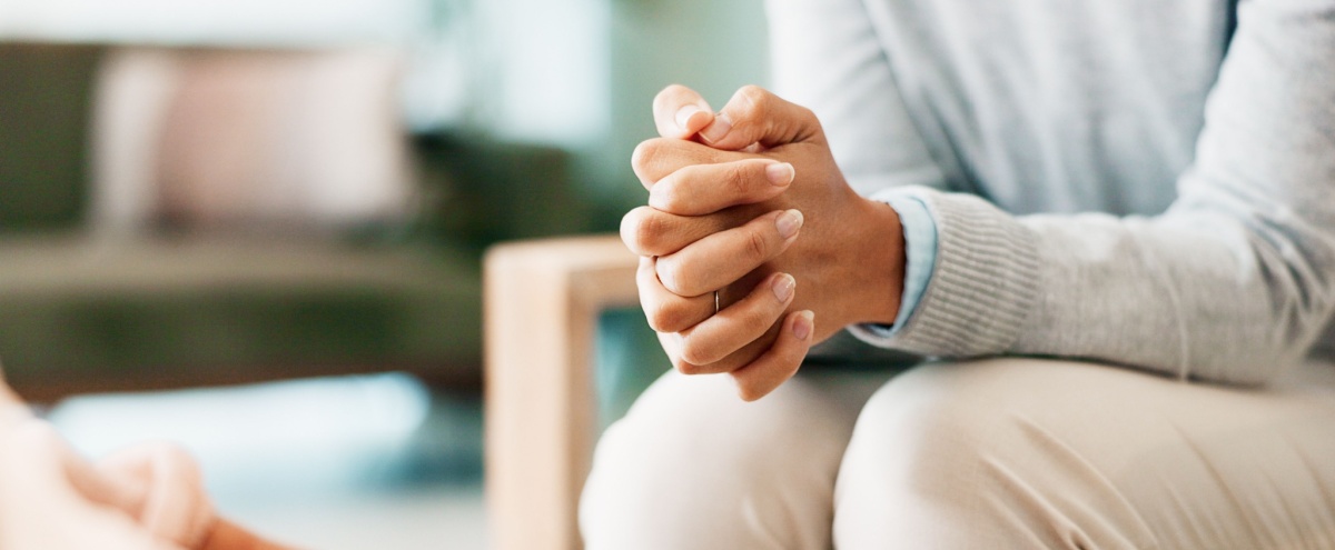A woman sitting with her hands clasped.