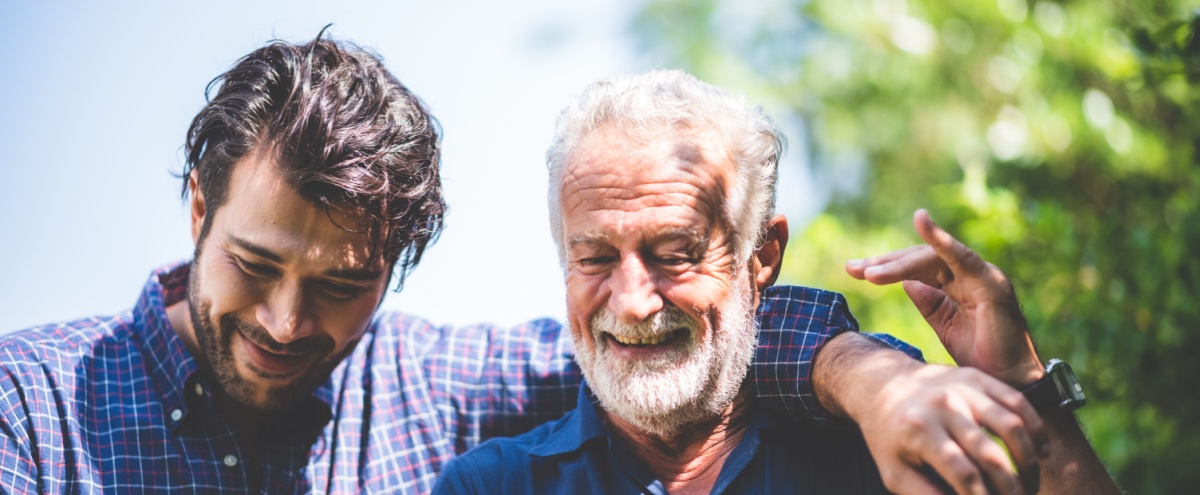 A father walking outdoors with his adult son.