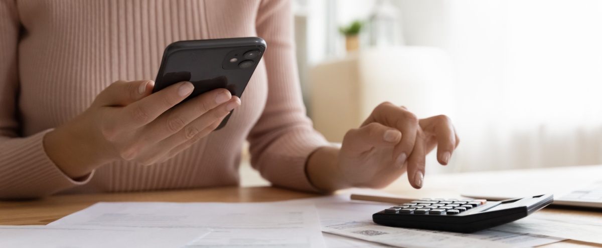A woman using a phone and calculator.