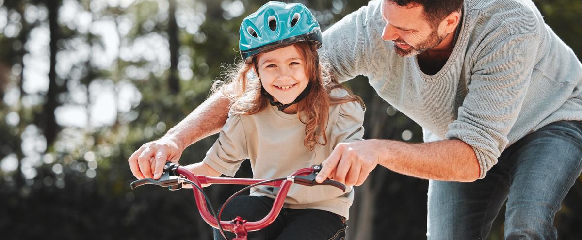 A father teaching his daughter to ride a bike.